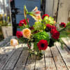 Festive arrangement of bold color and texture featuring fresh flowers and seasonal