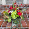 Seasonal arrangement featuring holly branches and other seasonal foliage combined with fresh
