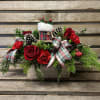 White wooden box filled with Christmas greens and pops of red flowers.