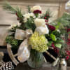 A winter themed arrangement featuring white roses, white carnations, a hydrangea, berries