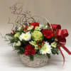 A festive basket with holiday blooms of red carnations, white chrysanthemums, berries