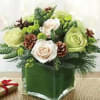 A modern evergreen and rose bouquet in a glass cube vase.