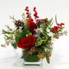 A charming holiday arrangement featuring red roses, berries, red amaryllis, winter greens