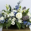 Lush blue and white centerpiece. Flowers may include white roses, blue thistle