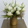 Lush arrangement of white double tulips with winter greenery. 