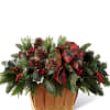 Assorted seasonal greens fill a honey color basket accented with red berries