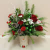 An arrangement that is filled with winter greens,  roses, carnations and