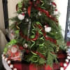 A MINI TABLETOP CHRISTMAS TREE MADE WITH FRESH CHRISTMAS GREENS, ADORNED IN