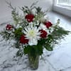 A festive arrangement of bright red roses and white seasonal flowers on