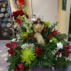 A winter arrangement filled with assorted seasonal flowers and winter greens accented