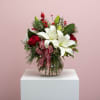 A sweet mix of white lilies, red roses, berries, and winter greens