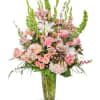 A large vased floral arrangement with white lilies, pastel roses, hydrangeas, and