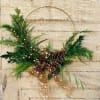 Evergreens, ribbon, berries and pinecones accent a 12&quot; gold hoop base for