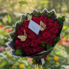 An opulent bouquet of deep red roses, elegantly wrapped, stands as the