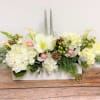 A modern take on a traditional centerpiece. White flowers and winter greens