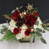 A gold cube filled with hydrangea, burgundy amaryllis, hypericum berries, roses, cedar