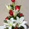 This arrangement of holiday cheer with red roses and white lilies with