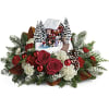 Set atop a magnificent bouquet of festive flowers and fresh Christmas greens