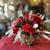 This arrangement features stunning red roses, red hypericum berries, mini carnations, frosted
