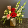 a fancy christmas arrangement with roses, snap dragons, protea and christmas greens