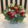 This arrangement includes premium blooms and festive holiday ornaments. 