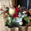 Protea, Roses, Berries, Holly, Peonies, with seasonal accents in a grey clay