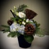 Blue hydrangea, white lisanthus and seasonal greens sit in blue velvet container