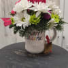 Rae and Dunn christmas mug filled with xmas greens and holiday flowers