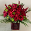A stunning holiday arrangement featuring vibrant red roses, green blooms, fresh pine