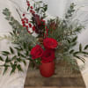 A vibrant red cylinder filled with red roses and winterberry, accented with