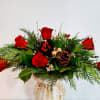 Traditional Christmas table centerpiece with flowers set into green container with floral