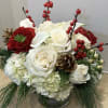 Traditional evergreen Christmas centerpiece features evergreens, berries, white mini callas, white roses
