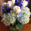 Pave arrangement of blue hydrangea, white roses and blue delphinium in a