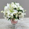 A bouquet of mixed white flowers in a glass vase decorated with