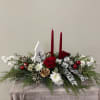 Double candle centerpiece includes winter greens, florals and a ceramic keepsake Christmas