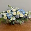 This wintery flower arrangement features classic white roses, lush blue hydrangea, and