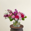 This arrangement features berry hues of carnations, daisies, roses, stock, and greens.