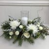 A Christmas centerpiece with all white flowers and natural Christmas greenery. Decorated