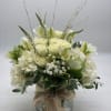A lush mix of fresh white flowers arranged in a cylinder vase