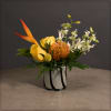 With an emphasis on a pincushion protea, accented by dendrobium orchis, roses