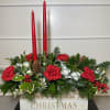 This holiday box arrangement features carnations, holly, pinecones, and Christmas greens with