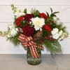 This arrangement features a holiday mix of evergreens, roses, chrysanthemums, carnations, stock