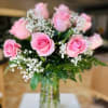 1 dozen light pink roses in a clear vase. 