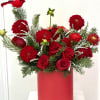 A vibrant holiday arrangement filled with rich red roses and dahlias, nestled