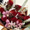 A rich winter bouquet featuring deep red roses, elegant pink orchids, and