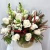 A graceful winter arrangement featuring creamy white roses and soft white snapdragons