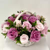 A charming white basket filled with purple, pink, and white roses, creating