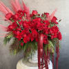 A luxurious Christmas arrangement featuring deep red roses and festive red pampas