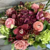 Lush burgundy hydrangea, roses, ranunculus, orchids &amp; assorted evergreens in a low