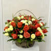 A radiant blend of orange and cream roses accented with red berries